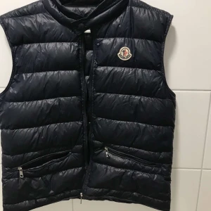 Moncler väst  - Säljer MONCLER väst, västen är it sönder den enda fel är att dragkedjan ramlade av så har inte haft på dragkedja på länge . Kan säljas billigare vid snabb affär, står ingen storlek men det passar till dem som har storlek S. (Färg:mörk blå)