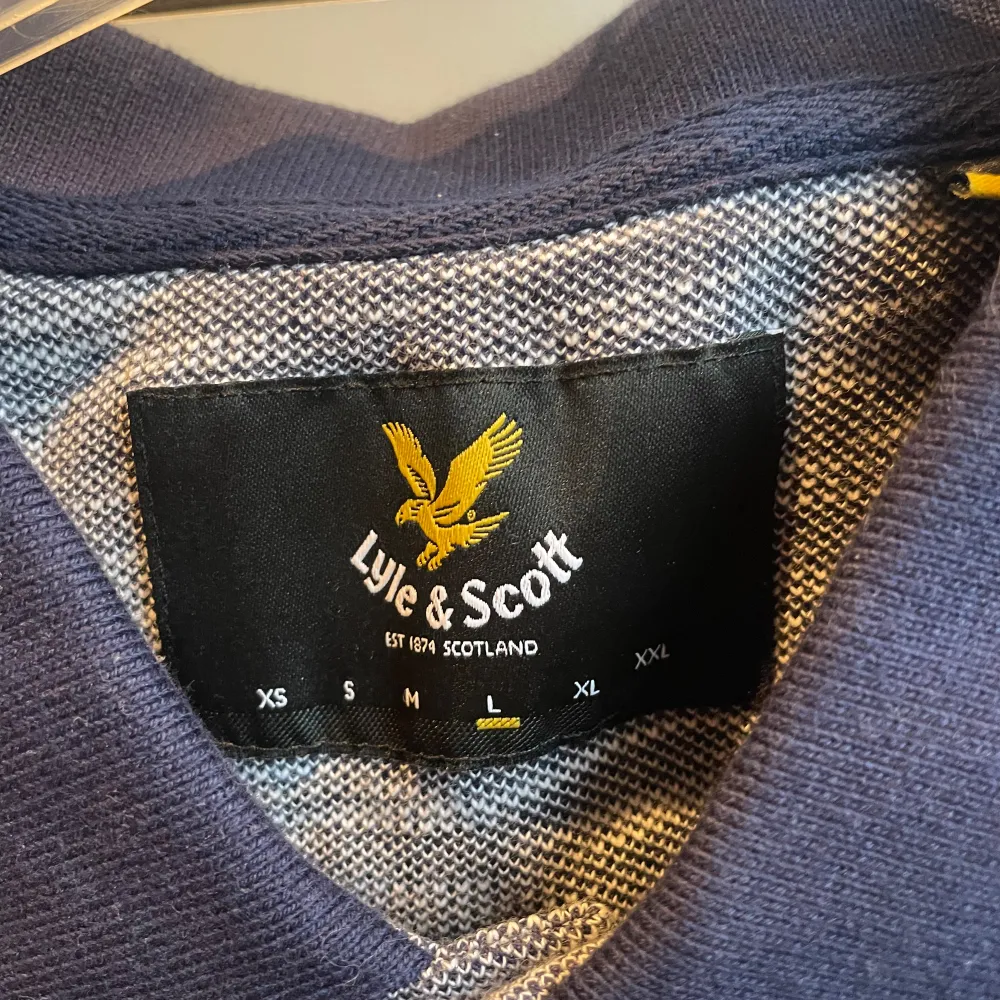 Oanvänd Gråblå pikétröja från Lyle & Scott. Inköpt på Lyle & Scott för ca 1år sedan. Normal i storleken. (Finns en extra knapp med).. T-shirts.