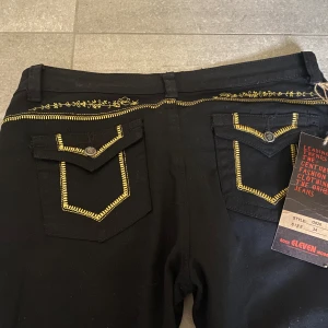 Coola vintage y2k lowwaist straightleg jeans med fickor blommor och detaljer  - Innerben: 78cm. Midja: 42 cm. Helt perfekt skick och nya med lapp på dessa raka jeansen med låg midja. Ända defekten är ett slags hål som bildats under ett av banden som man kan ha skärp i. Därav de låga priset men går säkert att sy ihop. Super fina💞