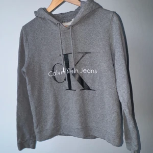 Calvin Klein hoodie XS/S - Grå Calvin Klein Hoodie med vitt & svart tryck, storlek S men passar XS. 