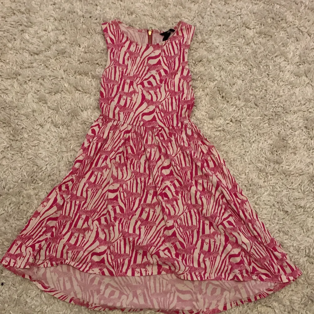 Säljer en rosa vit klänning med zebra mönster och zebror på i storlek XS.  Köpt på H&M och har bara varit använd 3 gånger av mig men är ärvd av en släkting. Klänningar.