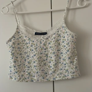 Linne - Tar snart bort min profil, köp du om du är intresserad! Ett linne som är vitt med blommor i blått, rosa och grönt. Den är liten i storlek, antingen som Xs eller S. Den är kort och är under navellängd. Bra skick, nästan oanvänd. 