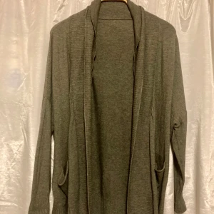 Mossgrön kofta, Stl 42/44  - Mossgrön kofta, bara använd några gånger, normal i storleken. Finns några mindre noppror och två små fläckar på ena ärmen, inget som stör (ej testat ta bort) Lappen bortklippt, kommer ej ihåg märke men kostade ngra hundra ny. Mjuk och skön. 