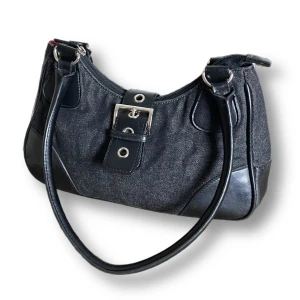 Y2K Väska  - En jättefin väska från Vezzano i fint skick. Grå/svart denimfärg. Slitningar finns under väskan annars är den i fint skick! Se sista bilden. MÅTT: Bredd 31cm (bredden är mått längs ner), höjd 16cm (måttet är mätt i mitten av väskan) & djup 9cm