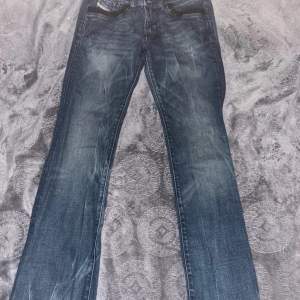 Ett par low waisted diesel jeans med utsvängda ben som har paljettdetaljer på bakfickorna och framfickorna