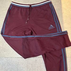 Adidas mjukisbyxor - Vinröda mjukisbyxor från adidas med blå logga i fint skick.