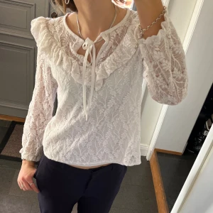 Vit blus med volanger - Vit spetsblus med volanger och snörning från Cherry Paris. Storlek M, passar även S. Fint skick. Använd gärna köp nu!