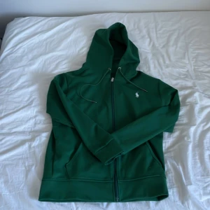 Grön Ralph Lauren zip - Säljer denna sköna Ralph Lauren zip i mörkgrön färg. Storlek S. Aldrig använd. Riktigt fräsch till våren/sommaren. Skriv om ni har några frågor eller liknande:)