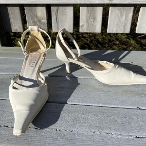 Vita 90-talsklackar - Ett par låga vita klackar i 90-talsstil med spetsig tå och ankelrem. Jättebekväma att gå i och lätta att styla till mycket. Fler bilder finns! 