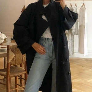 Svart Trenchcoat - Astrid Frank DK - Kommer inte längre till användning! Skickar gärna fler bilder, snygg svart trenchcoat som passar perfekt till våren och i ett tunt fint material. Mindre defekt vid ena fickan då en tråd spruckit