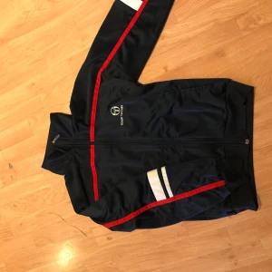 Retro Sergio Tacchini fullzip sweater - Skick 9,5/10 bara lappen som sitter lite löst inga andra brister. Storlek m-small men passar 170-180cm i längd. Gjord i Italien. Kan mötas upp i Stockholm för en snabb affär. Pris kan diskuteras och det är bara att höra av sig ifall ni undrar något:)