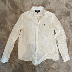 Ralph lauren linne skjorta - Säljer nu denna snygga linne skjorta från Ralph lauren. Skjortan är i storlek 14-16 år, vilket passar om man är 160-170 cm. Den sitter lite kort på mig som är 175 cm. Knappt använd, därav 10/10 skick.