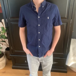 Ralph lauren skjorta  - Hej! Säljer nu en raffe skjorta med korta armar. Den är i mycket bra skick änvänd fåtal gånger Modelen på bilden är 178cm och väger 65 kg.Hör av dig vid eventuella frågor🌟