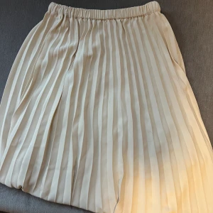 Volang kjol  - Säljer min volangkjol från Ginatricot i stl 32. Fin ljus beige färg och sitter snyggt på. Går till under knäna. 