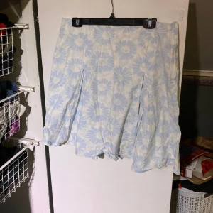 Kjol med blåa blommor - Vit kjol med blå blommor, behöver strykas innan användning 