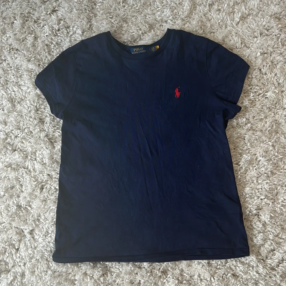 Blå t-shirt ifrån Ralph Lauren med en röd Ralph Lauren märke på. T- shirten är i nyskick då den aldrig är använd. Köptes för 899 säljer därför för ganska mycket men priset är förhandlingsbart vid snabba affärer!. T-shirts.