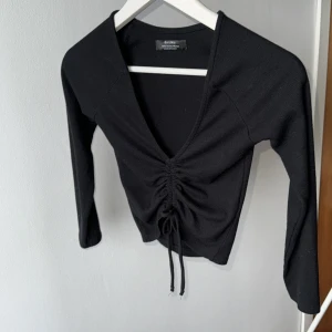 Svart croppad topp med snörning - Supersnygg svart crop topp från bershka med snören som man kan knyta som man vill, storlek XS. Superfint skick, kommer aldrig till användning.✨Använd gärna bundle funktionen, har flera billigare saker och kommer ut mer hela tiden🖤✨❤️💖