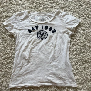 Vit t-shirt med tryck  - Vit t-shirt med blått trycka från Abercrombie & fitch, i ett väldigt skönt o mjukt material💞💞