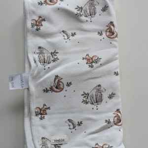 Vit filt med djurmönster från Newbie - En mjuk och bekväm vit filt från Newbie med ett sött mönster av olika djur, inklusive björnar, rävar och ekorrar. Filten är tillverkad i ett mjukt material och har en etikett med märket Mycket Fint skick 