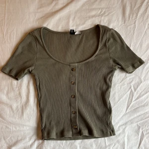 topp - söt, grön, kort och ribbad topp som har en fin ”u-ringning” med knappt längsmed framsidan🌸