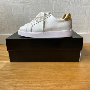 Ralph Lauren Skor strl: 35.5 - Säljer ett par vita och guldiga Ralph Lauren skor som är storlek 35.5. Den är bara använd tre gånger och har inga defekter.