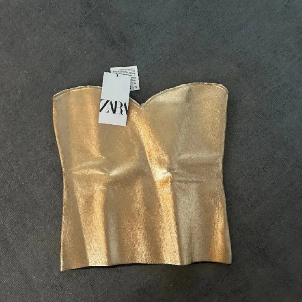 Helt oanvänd guldig tubtopp från Zara i strl S💕(Prislappen finns kvar) . Toppar.