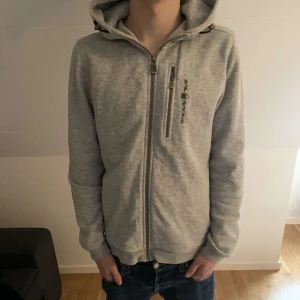 Sail Racing zip hoddie  - Säljer nu min gråa snygga och fräscha  Sail Racinng hoddie. Tröjan är använd några gånger men harr ett bra skick 8/10. Storlek s på tröjan. Tveka inte vid frågor 