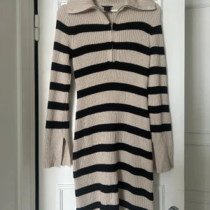 Ribbstickad klänning - Riddstickad klänning i storlek M, slits på armarna och dragkedja i fram. Nypris: 599kr