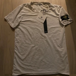 Stone island t shirt - Det är en stone island tisha från Farfetch, säljer pågrund den börjar bli för liten, tags o kvitto finns kvar/ skick 8/10 använd- skriv för fler frågor 