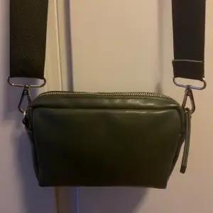 Liten mörkgrön/olivgrön axelväska/handväska i läderimitation! Har ett litet fack med dragked på utsidan och ett litet öppet fack inuti✨