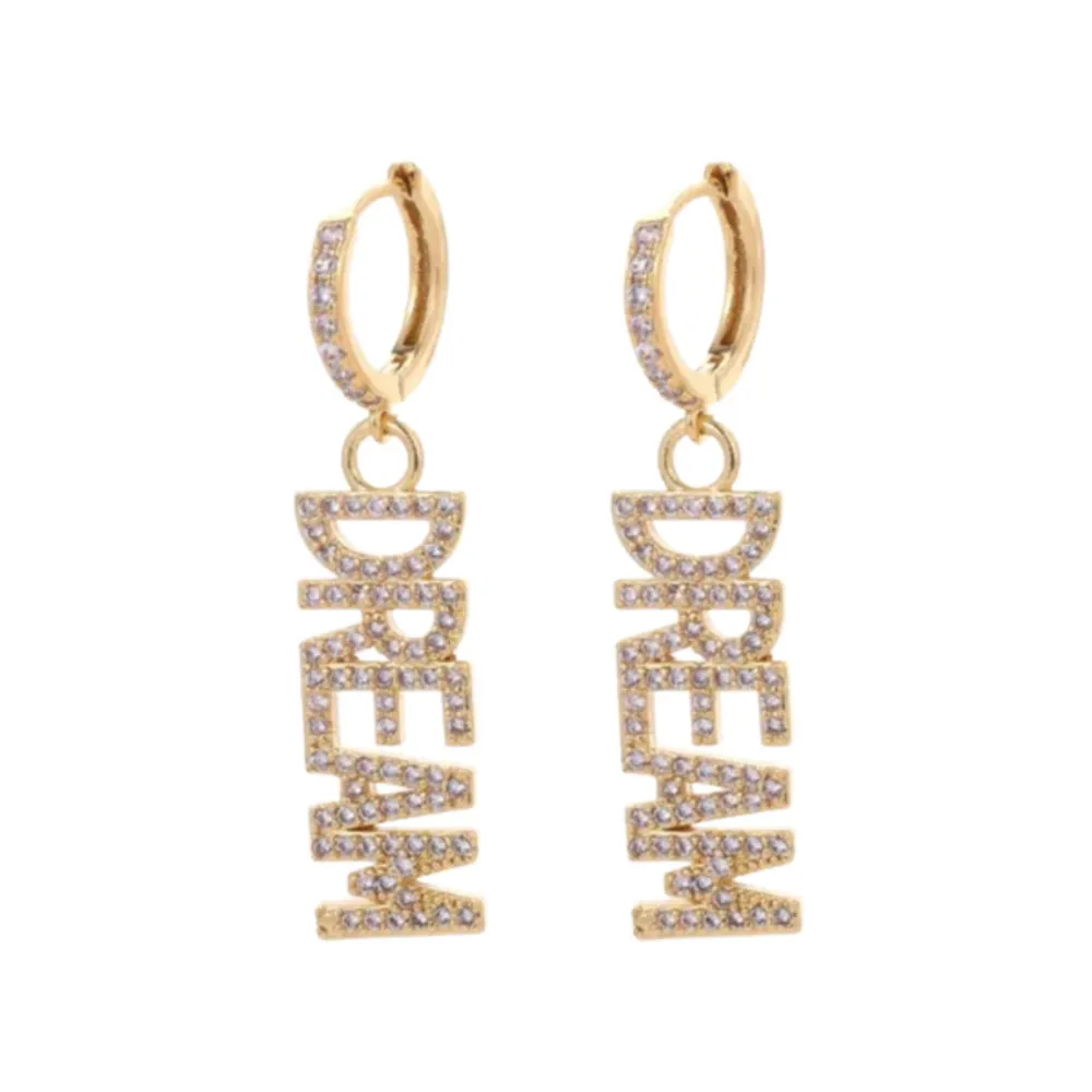 Material: Stainless Steel. Unveil the Dream Earrings by Bravery – a radiant dance of light, a testament to the power of dreams, each letter a sparkling beacon of hope, meticulously crafted with simulated diamonds.. Accessoarer.