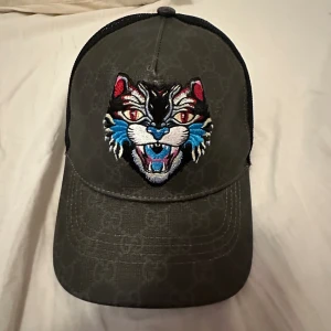 Gucci Keps Angry Cat - Helt ny inne extremt sällsynt limited edition Angry Cat Gucci keps. Den är top kvalite och skick. Den är oanvänd och i 10/10 skick. Priset är lite högre än vanligt eftersom den är så sälssynt och vacker. Övriga frågor kan diskuteras privat. 