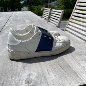 Valentino Open Sneaker - Klassiska Valentino Open som aldrig går fel. Det är en sällsynt blå färg på strip, otroligt snygga. Retail ligger på 7300kr. Skorna är i gott skick. Mvh, Elison