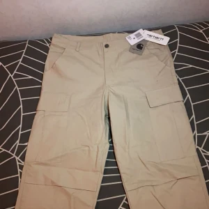 Carhartt Byxor - Helt nya Carhartt cargos i den efterfrågade färgen Beige, som är super fina och kan användas året runt. Passar bra med allting, speciellt för streetwear style. Byxorna är i storlek M. 