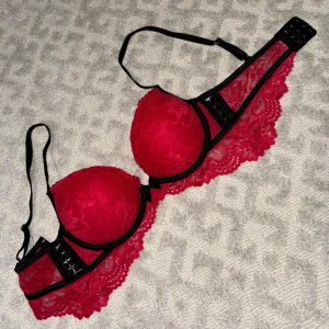 Röd bh med spets och svarta band - Storlek 75B, nyskick. Svart röd spets bh med mönster och rosett. Säljer flera liknande röda och andra färger i samma storlek eller liknande, köp med bundle om ni vill!❤️