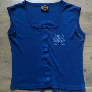 Harley Davidson Tee - Vintage Harley Davidson t-shirt/linne med knappar, går att knäppa upp helt. Bredd från armhåla till armhåla är 40 cm och totala längden från axeln ner är 45 cm.