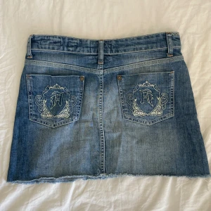 Snygg jeanskjol - Fin jeanskjol med snygga emblem/ broderi på fickorna!🪡🌀 Stl 28, stängs med knappar. 