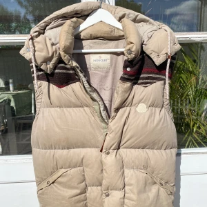 Moncler Beige Puffer Vest - Hej, säljer en Moncler väst i beige färg med stickade detaljer. Unik och omöjlig att få tag på. Perfekt för dig som inte vill se ut som resten. Nypris 12.000kr. Avtagbar huva. Storlek M. Använt skick. Pris kan diskuteras. Hör av dig vid intresse!
