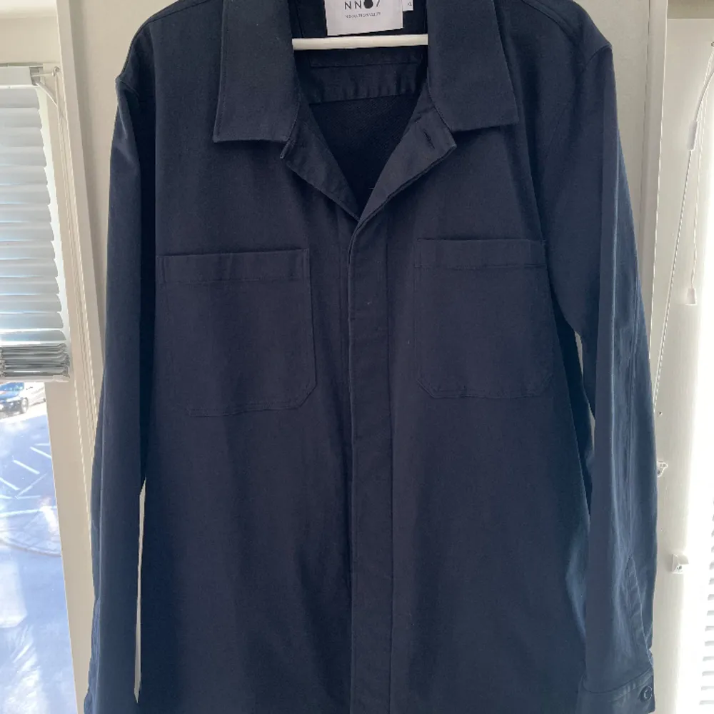 Overshirt från NN07 i färgen navy blue. Två bröstfickor samt en ficka på vardera sida vid magen. Använd ett fåtal gånger. Skick: 9/10 Nypris: 1999 kr. Jackor.