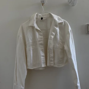 White Cropped Jeans Jacket - Vit croppad jeans jacka från HM Divided i storlek S. Använt bara 1 gång och är i jätte fint skick! Säljer den för att jag har bytt stil och inte använder jackan längre.
