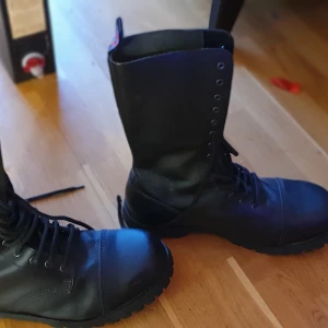Nevermind 14-hål - Nevermind 14 håls kängor med stålhetta. Aldrig använda!  Står storlek 47 i skorna men sitter perfekt på mig som har 45.  Storlek 45!  Skick 9/10  Tror jag köpte dom för ca 2000 kr  Finns i gävle