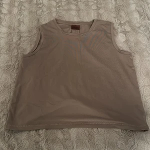 Tränings topp - Träningstopp från aimn med ”slits” baktill. Beige/brun. 