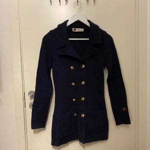 Busnel Victoria Navy storlek 32 - Busnels mest klassiska jacka Victoria. En tidlös blazer med åtta guldknappar och två fickor framtill. Normal i storleken. Storlek 32. Köpt för något år sen för 5800 kr. Säljs för 3900 kr. Finns att hämta i Nacka, Stockholm. Du betalar frakten.