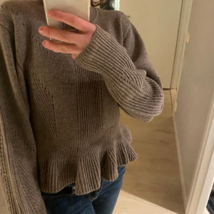Stickad tröja med volang - Säljer en jättefin stickad tröja med volang, är i storlek s/m och är som helt ny. Tröjan är lite brun/beige och har ett skönt material💕