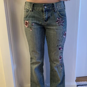 Vintage jeans med broderier  - jättesnygga bootcut jeans med lila blommiga broderier. lågmidjade men tyvärr lite för långa för mig.   midja: 39 cm innerbenslängd: 81 cm hela längden: 101 cm
