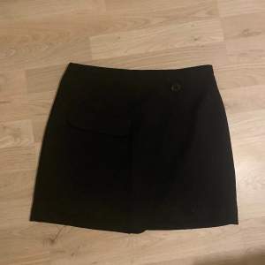 Fin svart kjol från H&M🌟Kjolen är kort och har en ficka och en knapp på framsidan. Säljer den då den ej kommer till använde