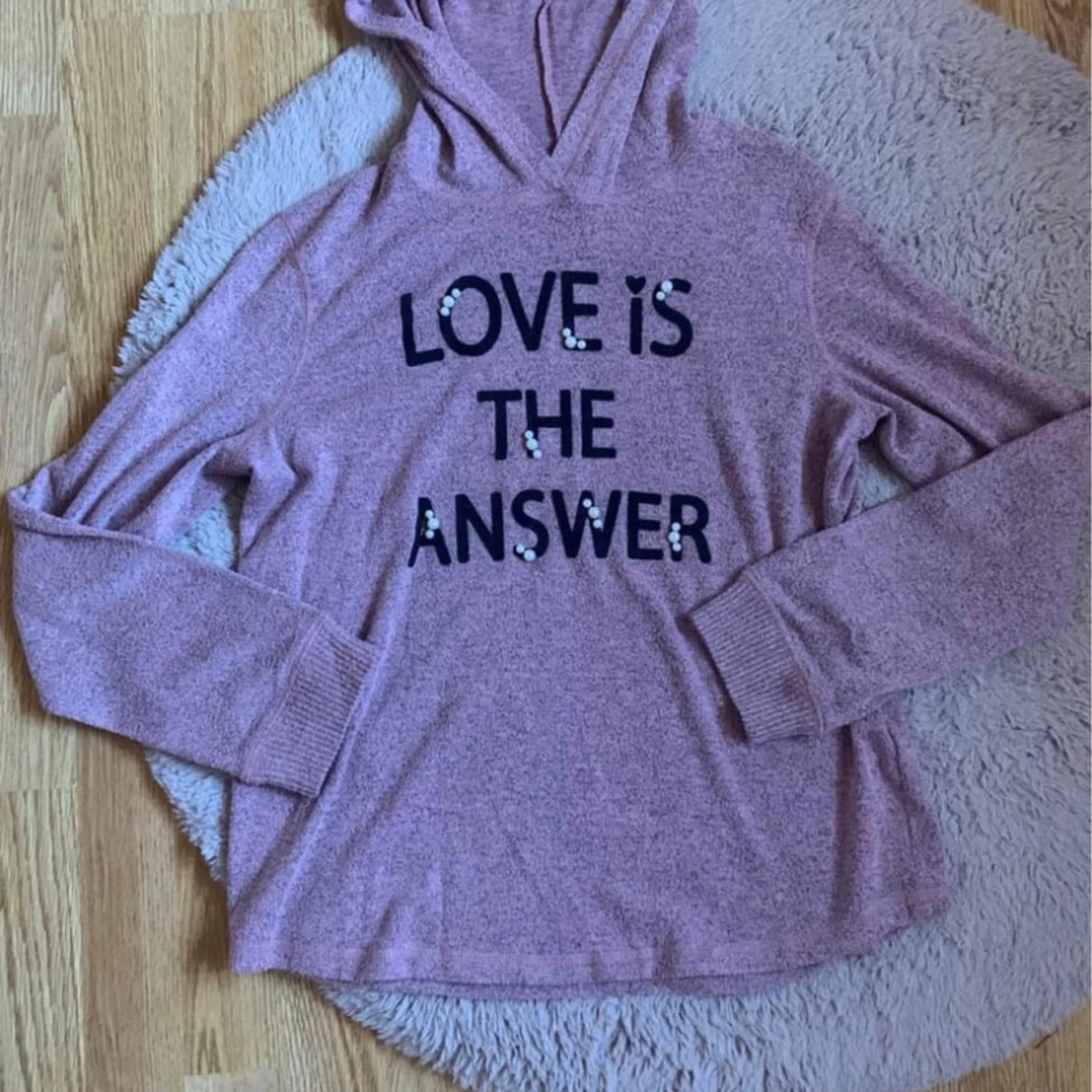 Rosa hoodie med texten 'LOVE IS THE ANSWER'