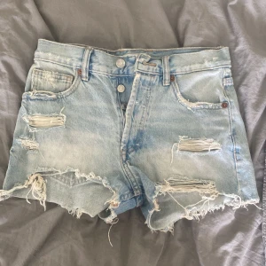 Ljusa jeansshorts från Zara - Ljusa jeansshorts från Zara med slitna detaljer och fransiga kanter. Shortsen har en klassisk femficksdesign och är tillverkade i bomull.