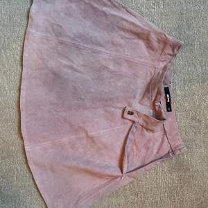 Söt kjol i äkta mocka från Never denim (bikbok gamla premium avdelning). Färgen är ljuslila/rosa. Mycket fint skick, knappt använd. 