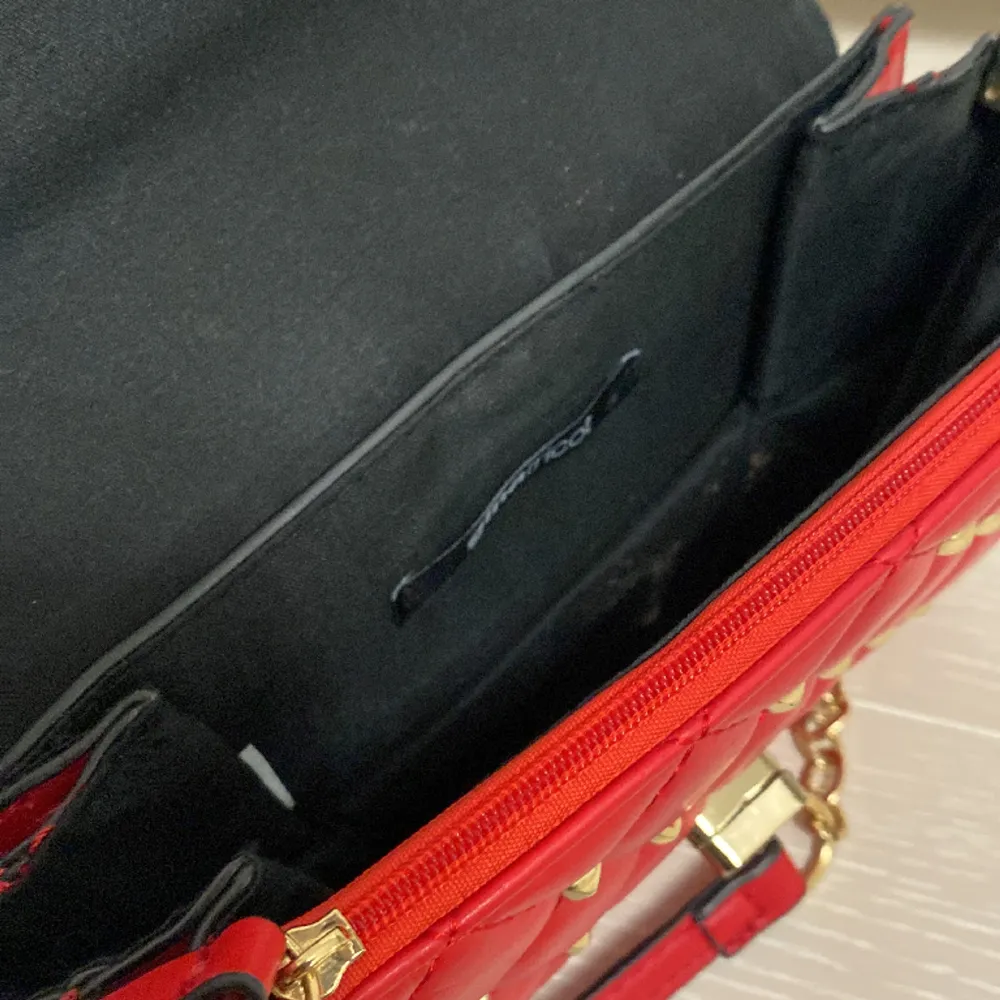 Jättefin röd väska med nitar från Gina Tricot 💗 använd väl och har några sminkgläckar i sig men tror dem skulle gå lätt bort med papper och vatten 💗 skriv för fler bilder eller frågor. Väskor.